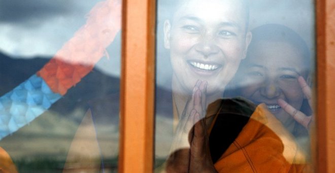 Dos monjas saludan a través de una ventana en el templo Naro Photang de la ciudad de Shey. - AFP
