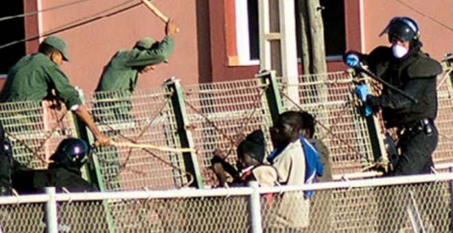 Agentes de la Guardia Civil y las fuerzas auxiliares marroquíes tratan de impedir que que varias personas migrantes salten la valla de Melilla.- CAMINANDO FRONTERAS