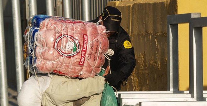 Una mujer porteadora carga con un fardo en el paso habilitado entre Ceuta y Marruecos.- APDHA