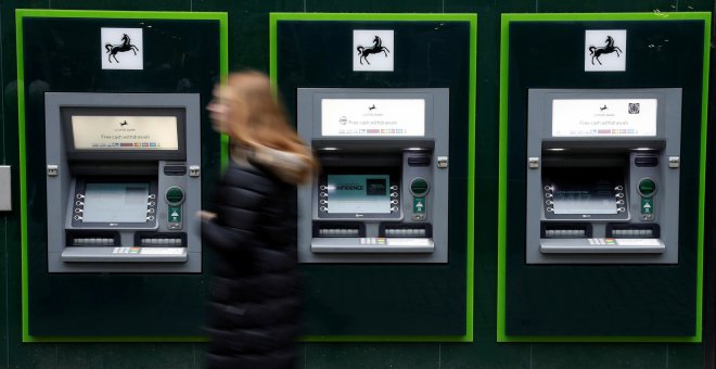 Una mujer pasa junto a los cajeros automáticos de una sucursal de Lloyds Bank en Manchester. REUTERS/Phil Noble