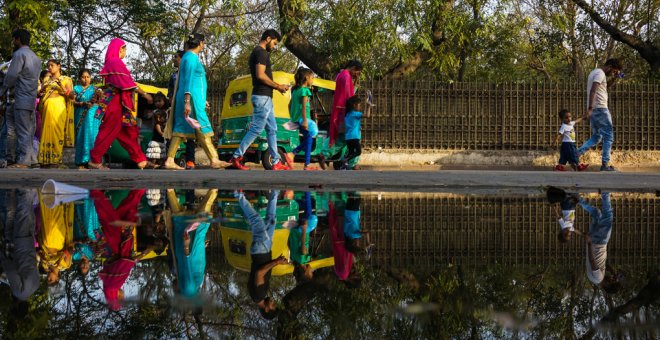 Varios habitantes de Nueva Delhi caminan por una calle encharcada. AFP/Chandan Khanna