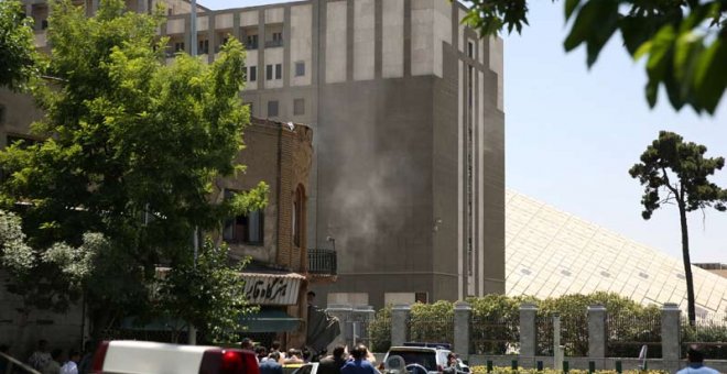 Fuerzas de seguridad permanecen en el exterior del edificio del Parlamento iraní, de donde se ver salir humo. | REUTERS