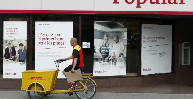 Un repartidor pasa ante una oficina del Banco Popular en Barcelona. EFE/Andreu Dalmau