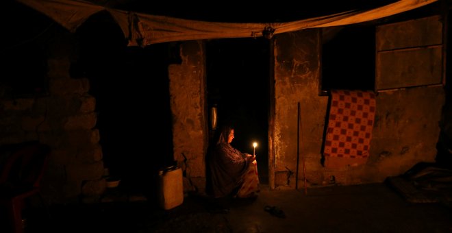 Mujer palestina sujeta una vela a la puerta de su casa durante un apagón en el Sur de la Franja de Gaza REUTERS/Ibraheem Abu Mustafa