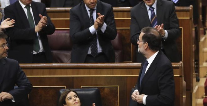El presidente del Gobierno, Mariano Rajoy (d, abajo), es aplaudido por la bancada popular tras la votación en el pleno del Congreso de los Diputados. /EFE