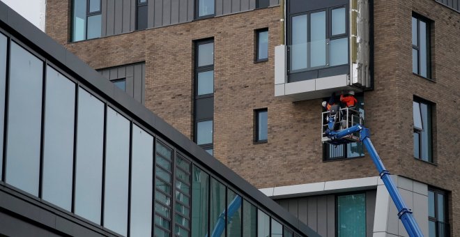 Unos trabajadores retiran el revestimiento inflamable en un bloque de viviendas en Manchester. REUTERS/Phil Noble