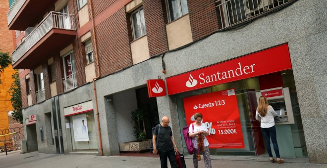 Una mujer utiliza el cajero automático de una oficina del Banco Santander, ubicado junto a un sucursal del Banco Popular, en Barcelona. REUTERS/Albert Gea