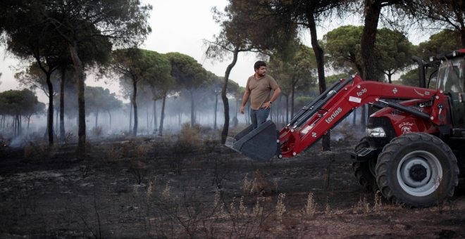 Un hombre se monta en un tractor mientras ayuda a apagar el incendio forestal cerca del Parque Nacional de Donaña en Mazagón. REUTERS/Jon Nazca