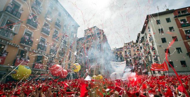 Cientos de personas alzan sus brazos al son de la música de los gaiteros que salen desde el Ayuntamiento de Pamplona para amenizar las calles del Casco Viejo de la ciudad tras el lanzamiento del tradicional chupinazo que ha abierto a las doce del mediodía