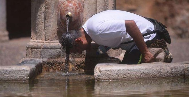 Un hombre se refresca en una fuente pública en el centro de Córdoba. | RAFA ALCAIDE (EFE)