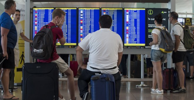 Varios viajeros consultan lo vuelos en los monitores del Aeropuerto de Barcelona-El Prat. EFE/Quique García