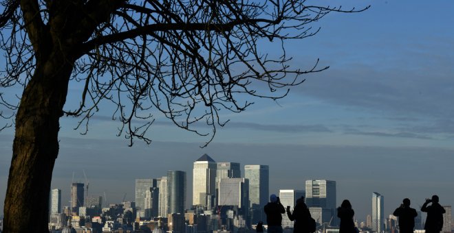 Varias personas toman fotos desde el Parque Greenwich de Canary Wharf, el distrito financiero londinense donde tienen su sede gran número de bancos internacionales y oficinas. AFP/Ben Stansall