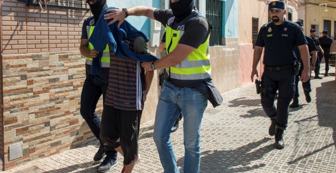 Agentes de la policía llevan detenido a uno de los sospechosos de participar en una red yihadista, en Melilla. REUTERS/Jesus Blasco de Avellaneda