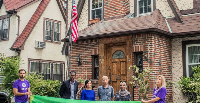 Integrantes de Oxfam sostienen una pancarta de apoyo a los refugiados frente a la casa de la infancia de Trump. / Reuters