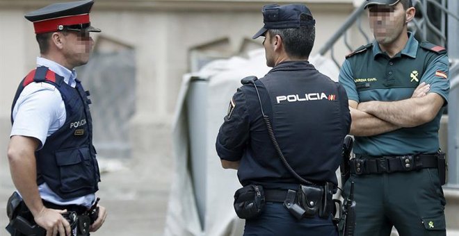 Un mosso, un policía nacional y un guardia civil vigilan el exterior del edificio de la Delegación del Gobierno en Catalunya, durante la reunión de coordinación de los cuerpos de seguridad sobre el 1-O. EFE/Andreu Dalmau