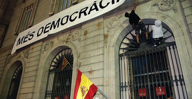 Dos personas intentan arrancar la pancarta de "Mès Democràcia" colgada en el ayuntamiento de Barcelona EFE/Juan Carlos Cárdenas