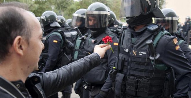 Un hombre ofrece un clavel a un agente de la Guardia Civil en el centro de votación de Sant Julià de Ramis (Girona) donde inicialmente tenía previsto votar el presidente de la Generalitat, Carles Puigdemont, en el referéndum independentista del 1-O./ EFE