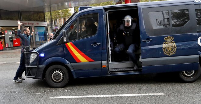 Un manifestante se coloca delante de una furgoneta de la Policía Nacional cerca de un colegio electoral en Barcelona durante el referéndum del 1-O. REUTERS/Yves Herman