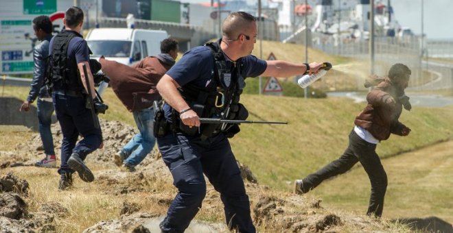 Fotografía de junio de 2015 de un policía gaseando a un inmigrante en Calais. - AFP