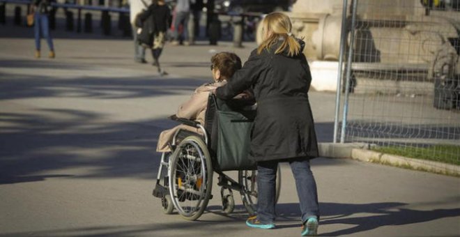 Una mujer mayor pasea con su cuidadora. EFE