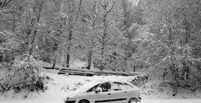 Un coche permanece atascado en la nieve en el Alto de Mezquiriz donde, tras el último temporal de nieve, frío y viento. /EFE