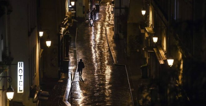 Una mujer camina sola por la calle bajo la luz de las farolas. EFE