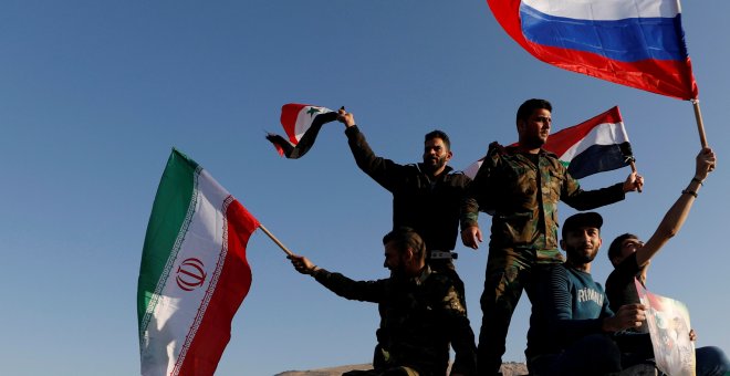 Sirios ondean las banderas de Irán, Rusia y Siria en protesta por los ataques en Damasco. /REUTERS