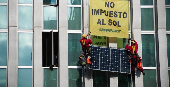 Activistas de Greenpeace subiendo una placa solar por la fachada del Ministerio.