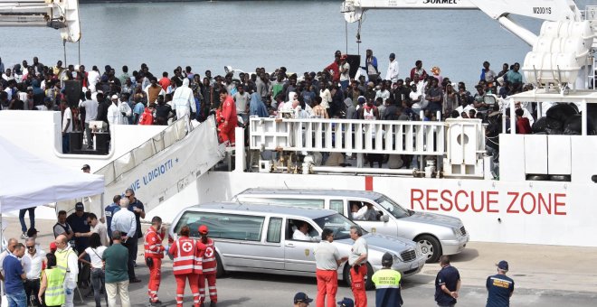 Dos coches funerarios aguardan a que varios oficiales desembarquen los cadáveres de dos inmigrantes a la llegada de la patrullera de la Guardia Costera Diciotti al puerto de Catania (Italia). EFE/ Orietta Scardino