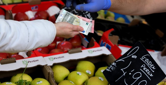 Una cliente paga la compra en un puesto de fruta en un mercado de Madrid. REUTERS/Sergio Perez