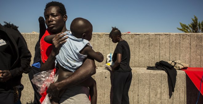 Una mujer subsahariana sostiene a su hijo antes de ser trasladados a otra parte del puerto de Algeciras. Cerca e 400 migrantes han pasado varias días enteros en los barcos de rescate o en el suelo por falta de espacio en otros lugares. JAIRO VARGAS