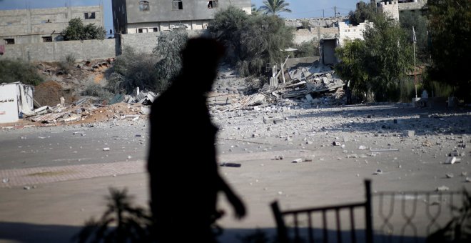 Un miembro de las fuerzas de seguridad palestinas de Hamas camina frente a las ruinas de un edificio tras un ataque aéreo israelí. / REUTERS - MOHAMMED SALEM