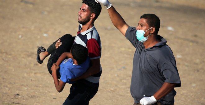 Dos hombres trasladan a un joven palestino herido durante las últimas protestas contra Israel. - REUTERS