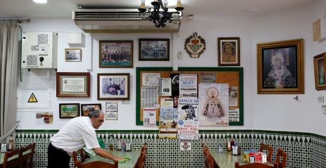 Un camareno limpia una mesa en el restaurante donde trabaja, en Chipiona (Cádiz). REUTERS / Marcelo del Pozo