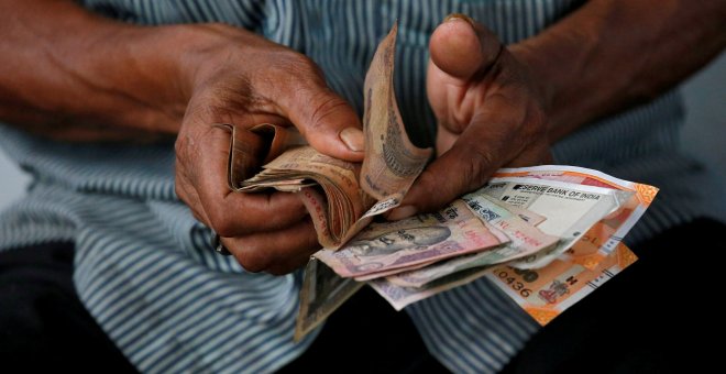 Un hombre maneja un fajo de billetes de rupias, en la ciudad india de Kolkata. REUTERS/Rupak De Chowdhuri