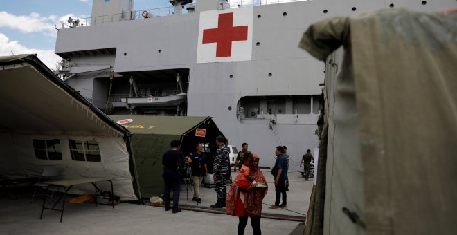 Una mujer sostiene a su hijo mientras espera tratamiento en el barco del hospital de la Armada de Indonesia. REUTERS