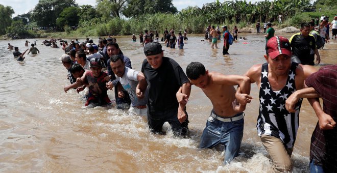Decenas de personas de la caravana de centroamericanos se unen entre ellas para poder atravesar el río Suchiate, la frontera natural entre Guatemala y México. | Leah Millis / Reuters