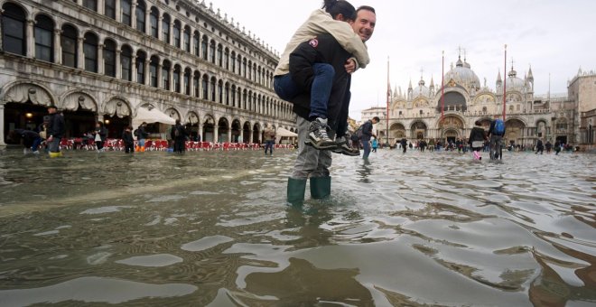 Un hombre carga a sus espaldas con su hija en la Plaza de San Marco de Venecia, inundada como consecuencia del temporal de lluvias. Andrea Merola/EFE