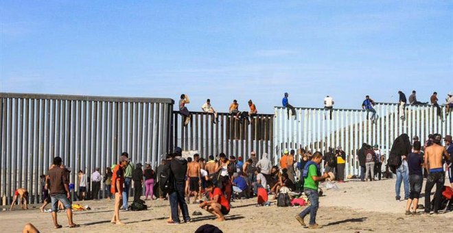 Integrantes de la primera caravana de centroamericanos escalan el muro fronterizo en Tijuana. (JOEBETH TERRIQUEZ | EFE)