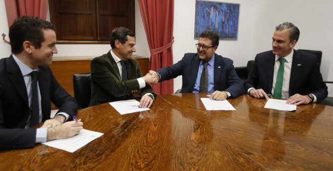 Los líderes andaluces del PP, Juan Manuel Moreno Bonilla, y de Vox, Francisco Serrano, estrechan las manos en presencia de los secretarios generales del PP, Teodoro García Egea, y de Vox, Francisco Javier Ortega Smith, durante la reunión en el Parlamento