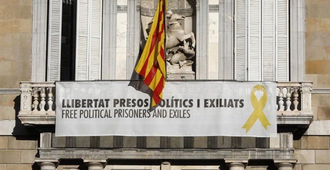 Vista del cartel reclamando la libertad de los líderes independentistas presos y un lazo amarillo en la fachada del Palau de la Generalitat. - EFE