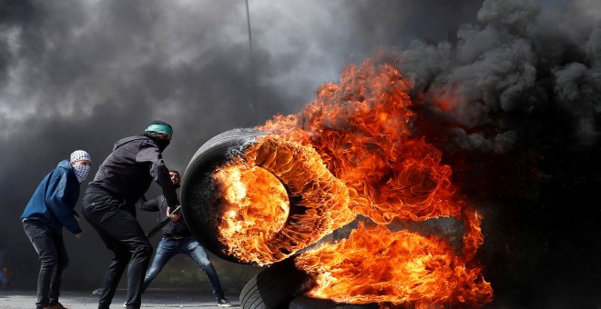 Un manifestante palestino mueve un neumático en llamas durante los enfrentamientos con las tropas israelíes. Reuters