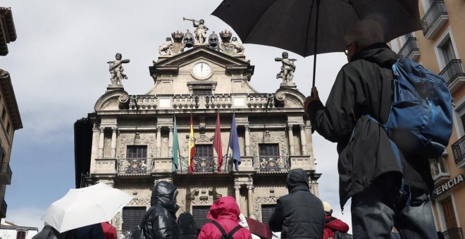 Un grupo de turistas se protegen con sus paraguas de la lluvia junto al Ayuntamiento de Pamplona, uno de los lugares preferidos para la Semana Santa. EFE