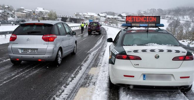 Efectivos de la Guardia Civil trabajan para descongestionar una retención por nieve en la autovía A-52, en Ourense. Las nevadas y las bajas temperaturas registradas en las últimas horas han provocado complicaciones desde primera hora de este sábado en la