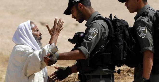 Un palestino discute con soldados israelíes mientras un buldócer destruye una granja y unas tierras de cultivo usadas para criar ovejas en la zona de Masafer, al sur de Hebrón (Palestina). (ABED AL HASHLAMOUN)