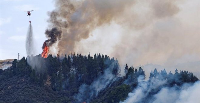 Un helicóptero echa agua sobre las llamas. - EFE