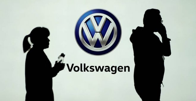 Dos personas pasan delate del logo de Volkswagen en la Feria del Automóvil de Shangai. (REUTERS)