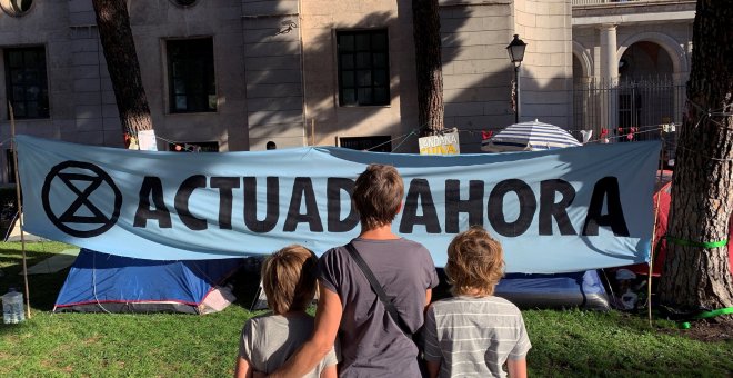 08/10/2019.- Una familia observa el campamento de activistas climáticos, que se instaló junto al Ministerio para la Transición Ecológica. / EFE - DANIELA GONZÁLEZ