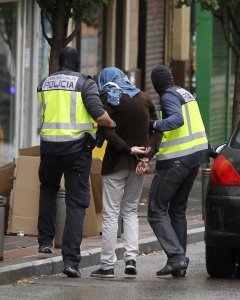 Dos efectivos de la Policía acompañan a una persona detenida en la operación desarrollada en Madrid contra un grupo vinculado al Estado Islámico. EFE/Víctor Lerena