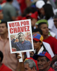 Un seguidor del presidente venezolano Nicolas Maduro con una pancarta con la imagen del fallecido Hugo Chavez. REUTERS/Carlos Garcia Rawlins
